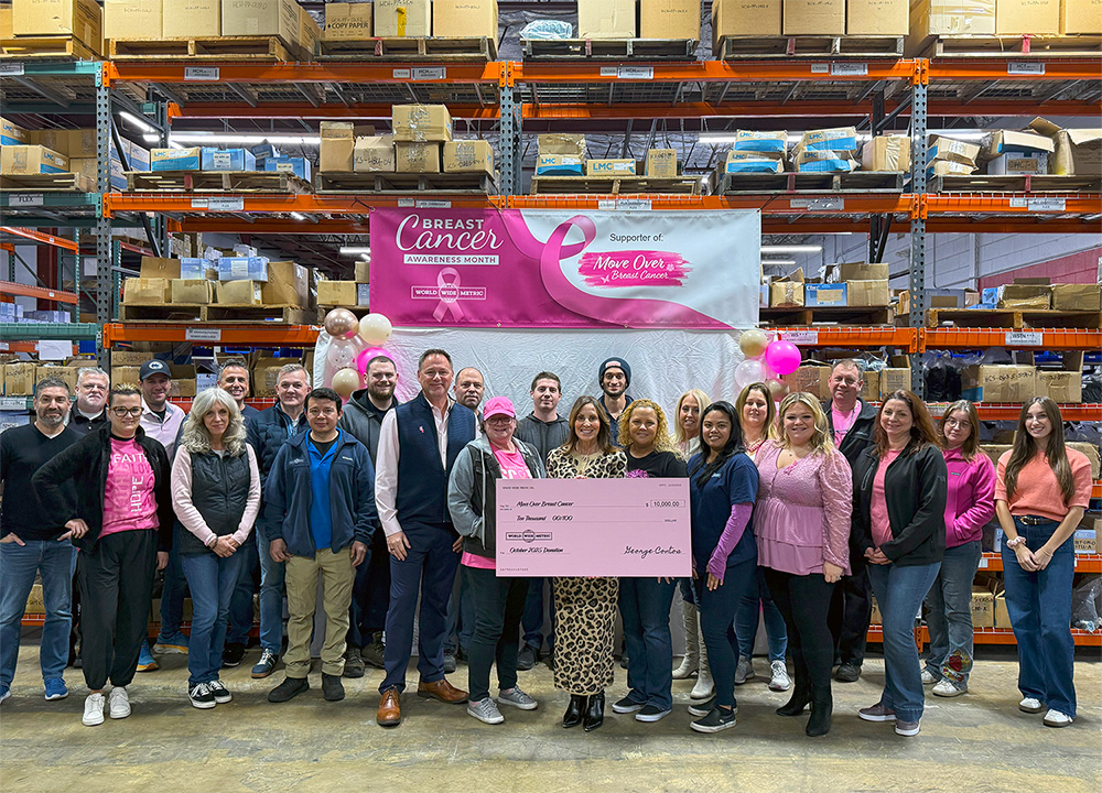 Large group of World Wide Metric employees presenting a donation check to Move Over Breast Cancer inside the warehouse