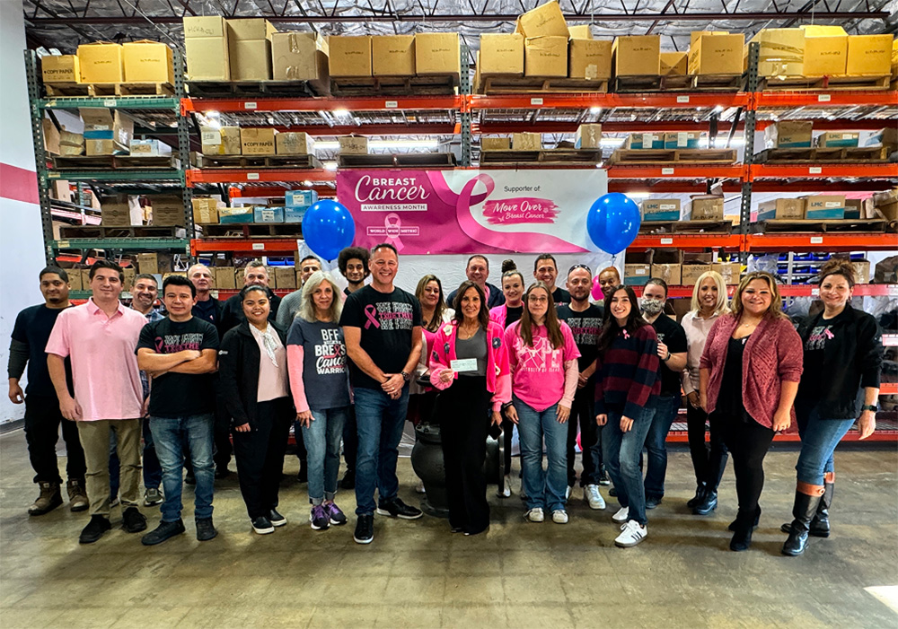 Large group of World Wide Metric employees celebrating Breast Cancer Awareness Month inside the warehouse