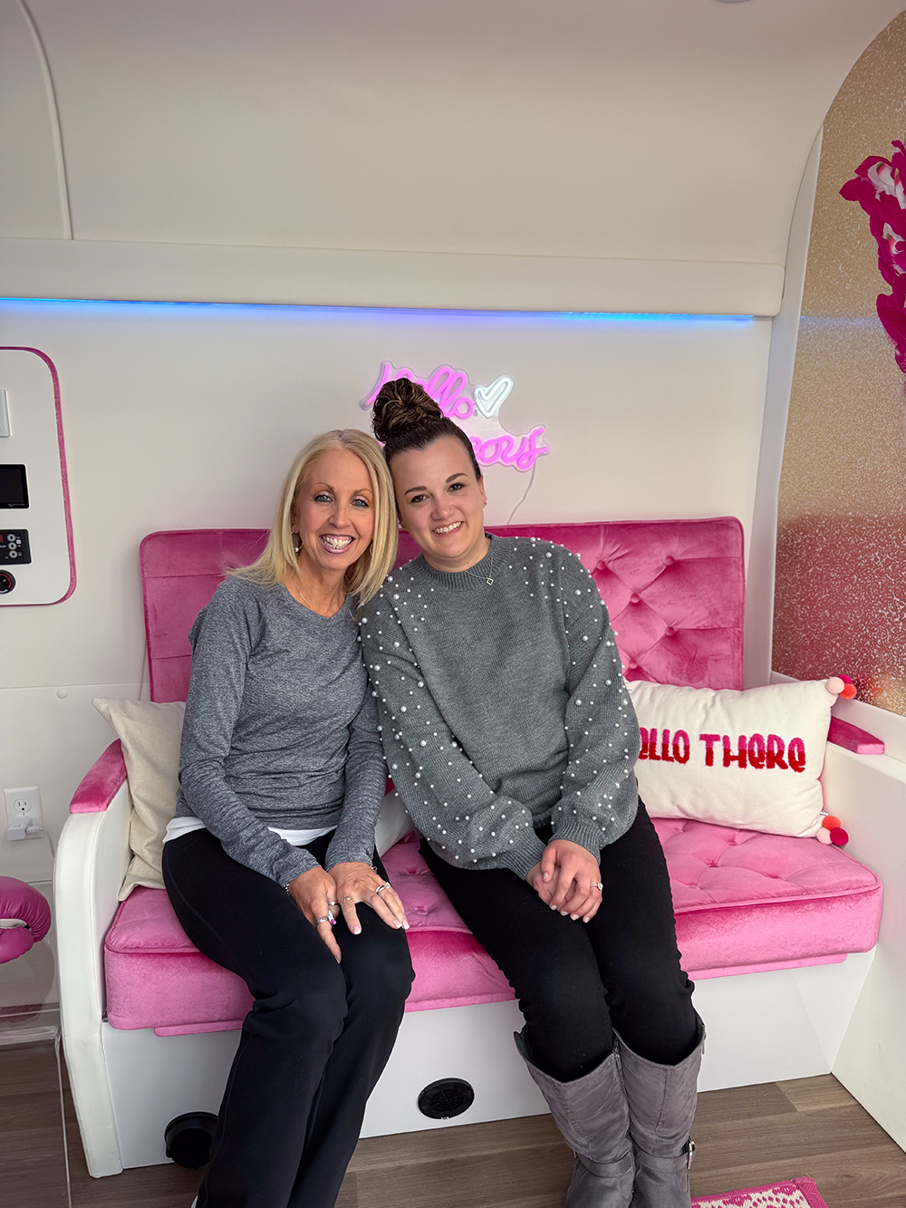 Two women seated inside the Mobile B Lounge at a Breast Cancer Awareness event