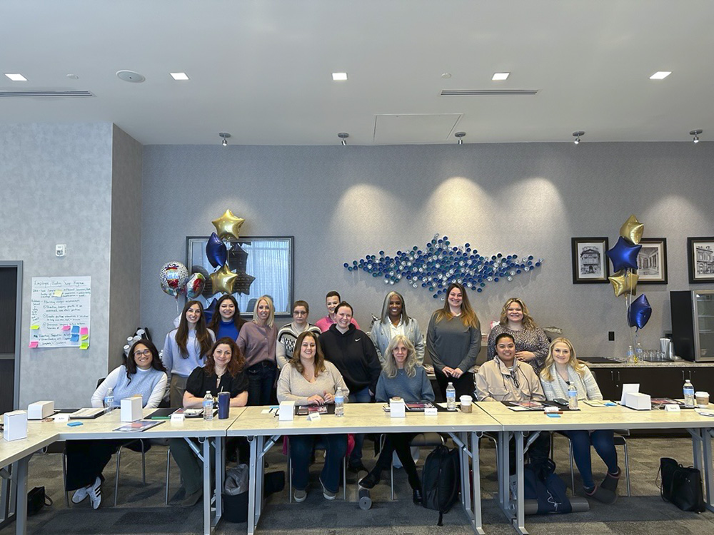 Group of Women Who Metric attendees seated and standing in a conference room with star balloons