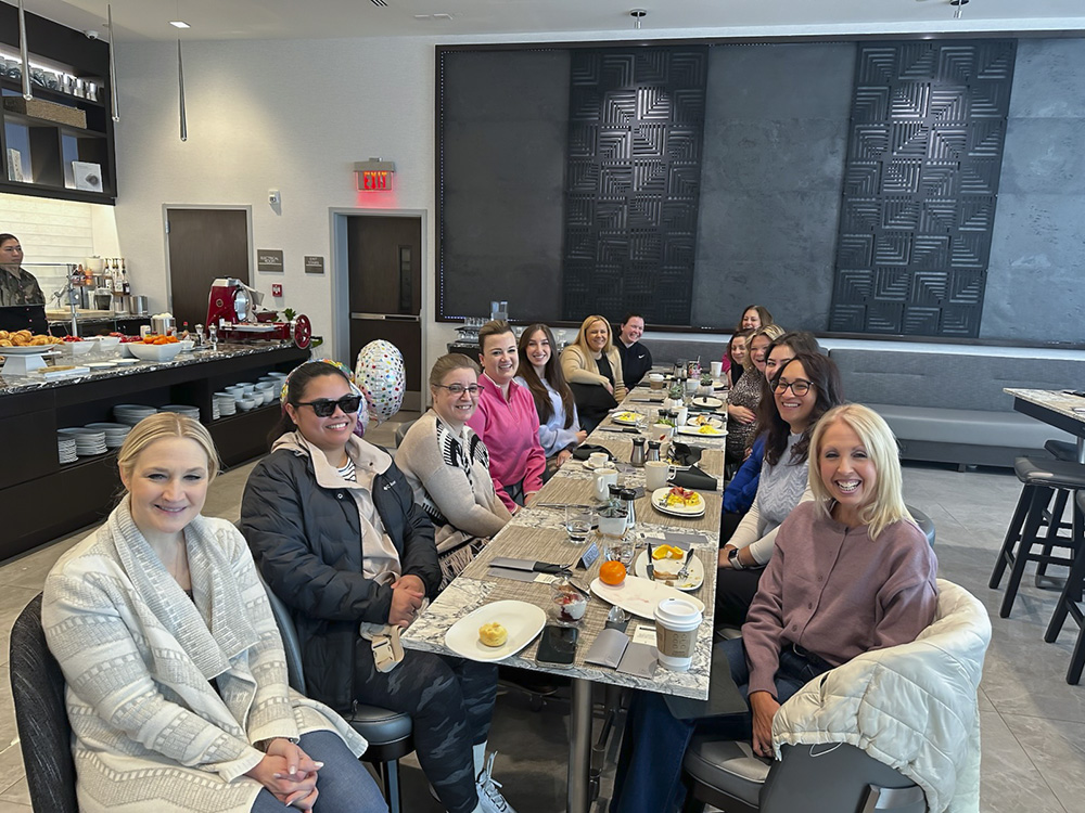 Women Who Metric members gathered around a long dining table at a group breakfast