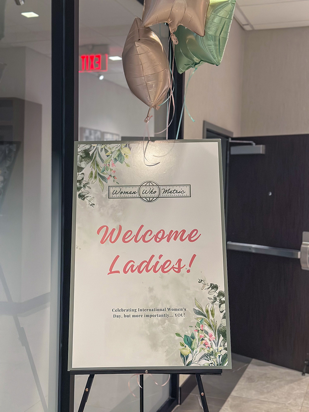 Women Who Metric Welcome Ladies sign on an easel with star balloons